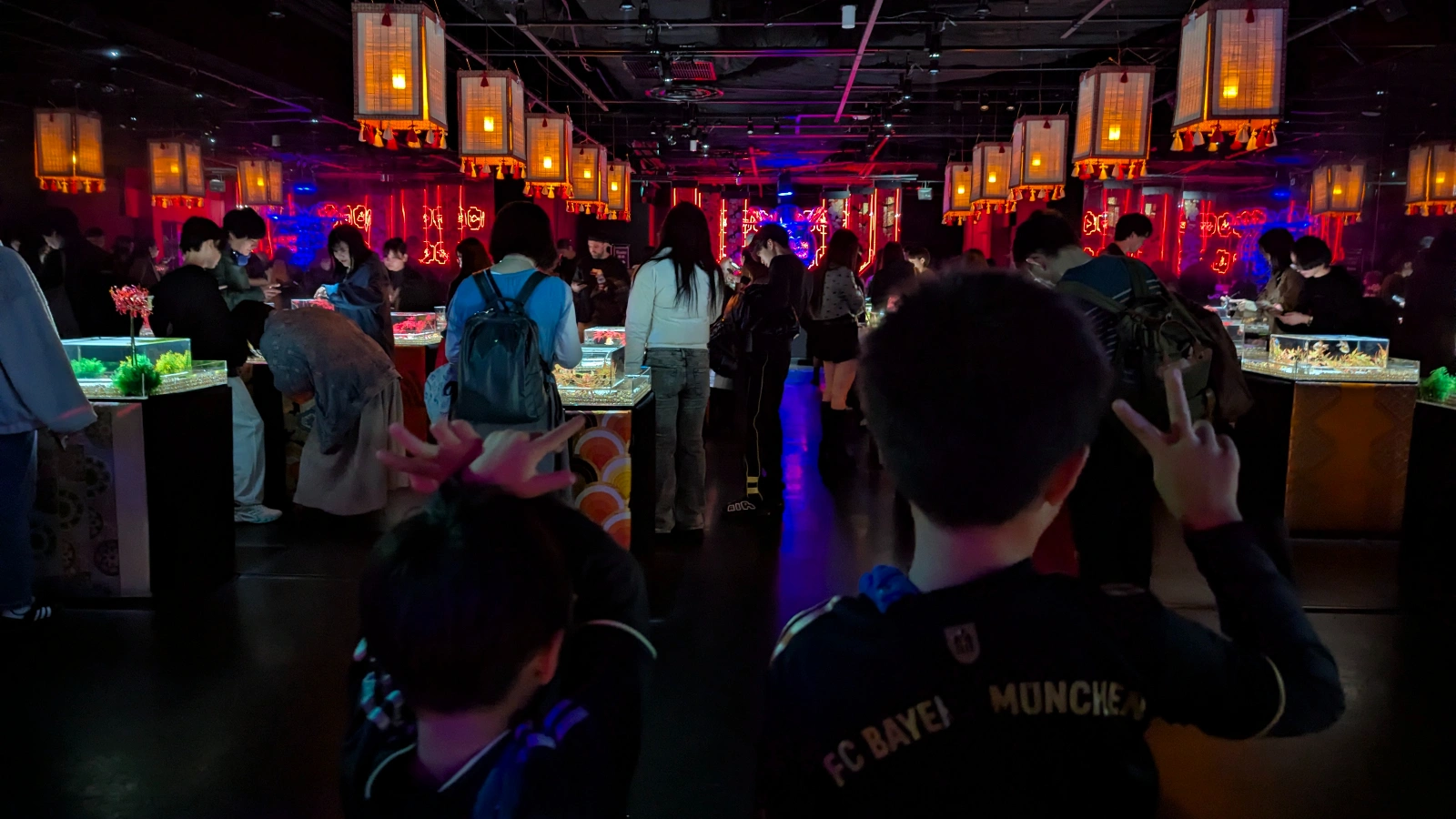 Visitors exploring the lantern-lit hall filled with small goldfish tanks at Art Aquarium Museum Ginza.
