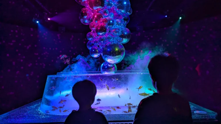 Kids viewing the NEO Oiran goldfish installation with glowing disco balls at Art Aquarium Museum Ginza in Tokyo.