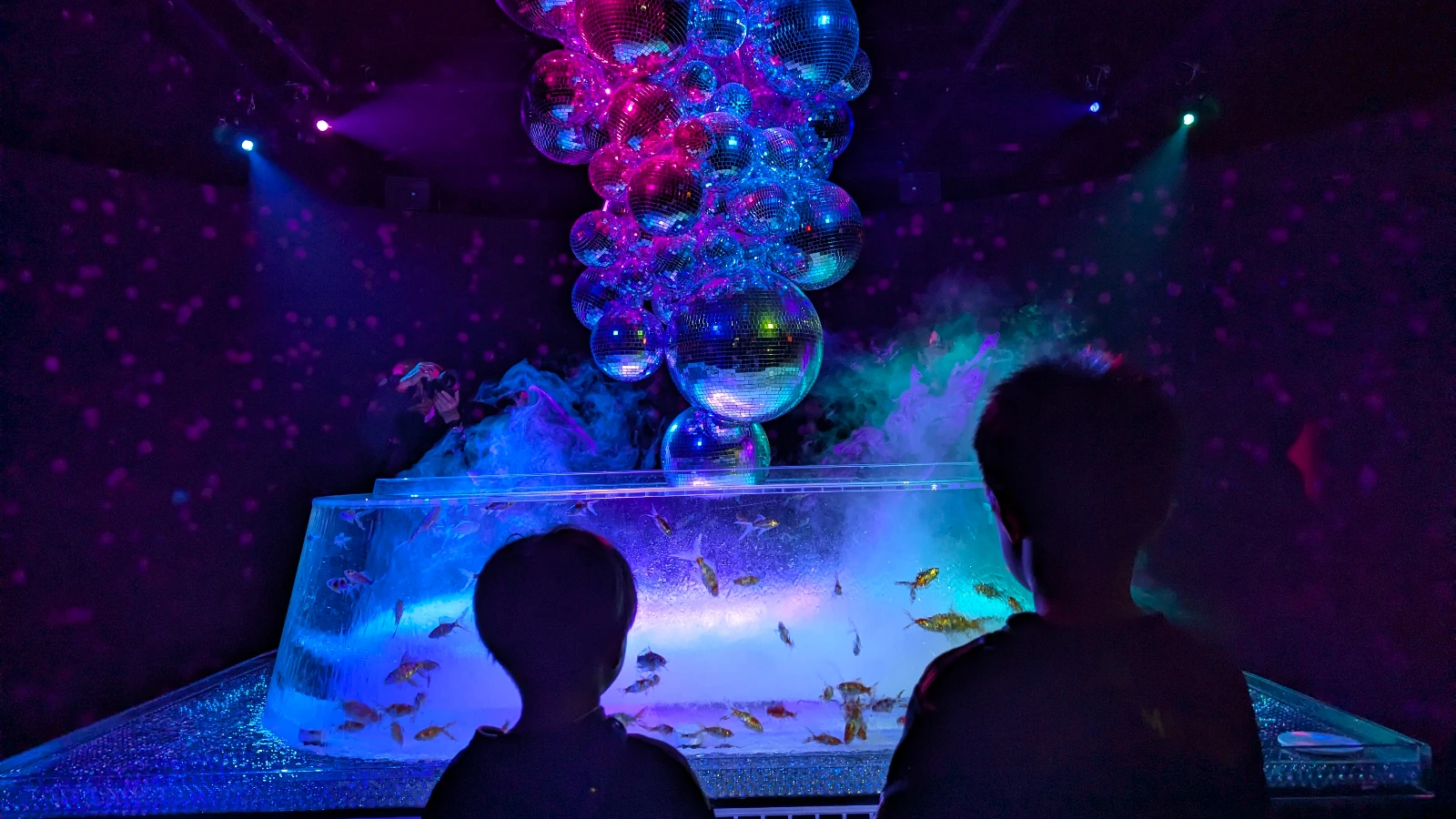 Kids viewing the NEO Oiran goldfish installation with glowing disco balls at Art Aquarium Museum Ginza in Tokyo.