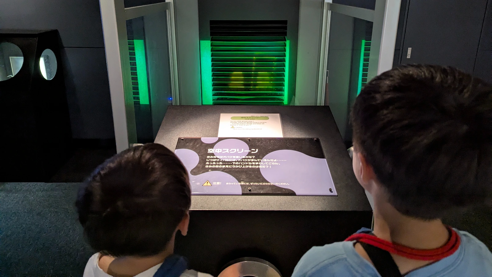 Kids watch the floating Air Screen display at Asahikawa Science Museum, observing how light reflections create moving images in mid-air.