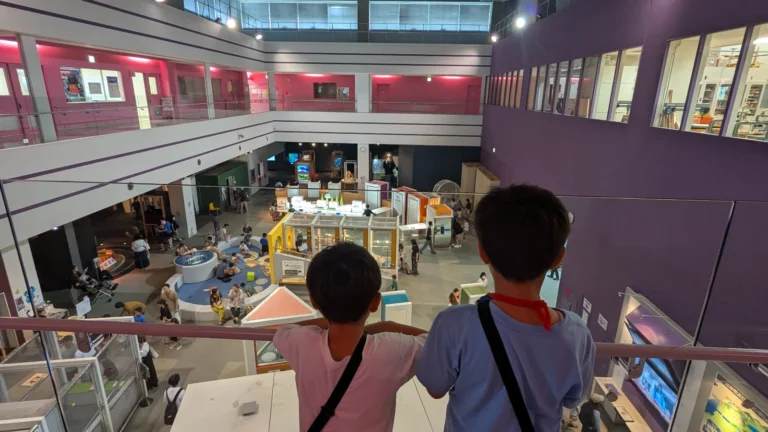 Two kids observe the interactive exhibits and open atrium inside the Asahikawa Science Museum, one of the best indoor attractions for families.