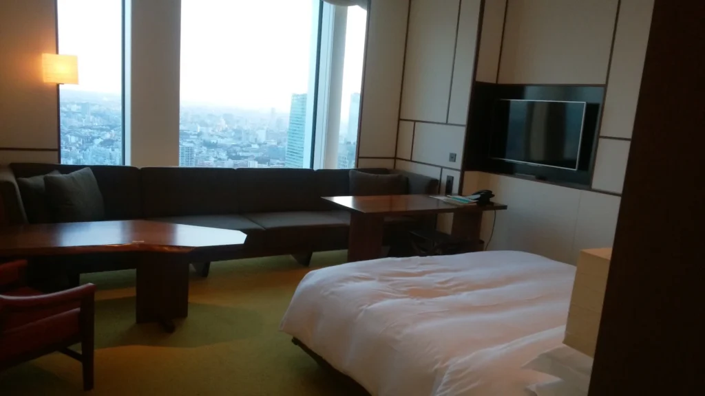 A spacious family hotel room in Japan with panoramic city views, modern furniture, and large windows, ideal for parents traveling with kids.