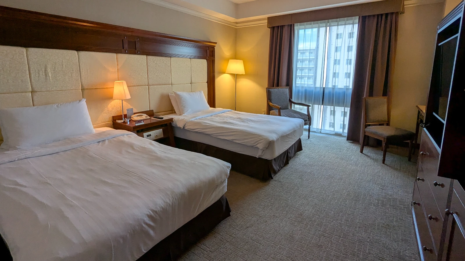Japanese hotel room with twin beds, warm lighting, and traditional decor, suited for family travelers.