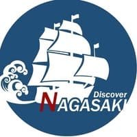 Circular blue logo for Discover Nagasaki, featuring a stylized white sailing ship on waves with red and white text.