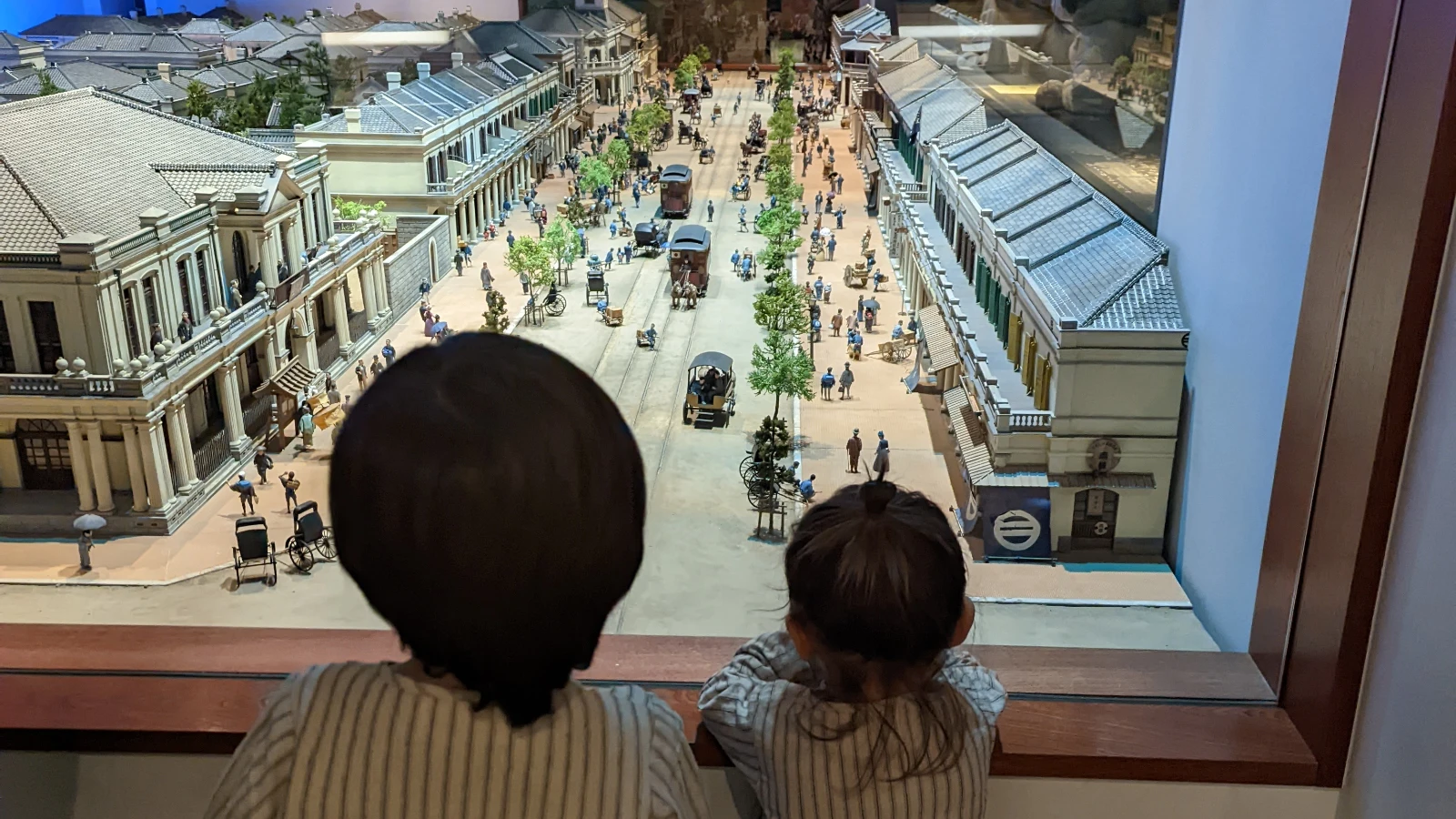 Two children looking at a detailed Edo-Tokyo Museum diorama showing old Tokyo streets, trams, and daily life.