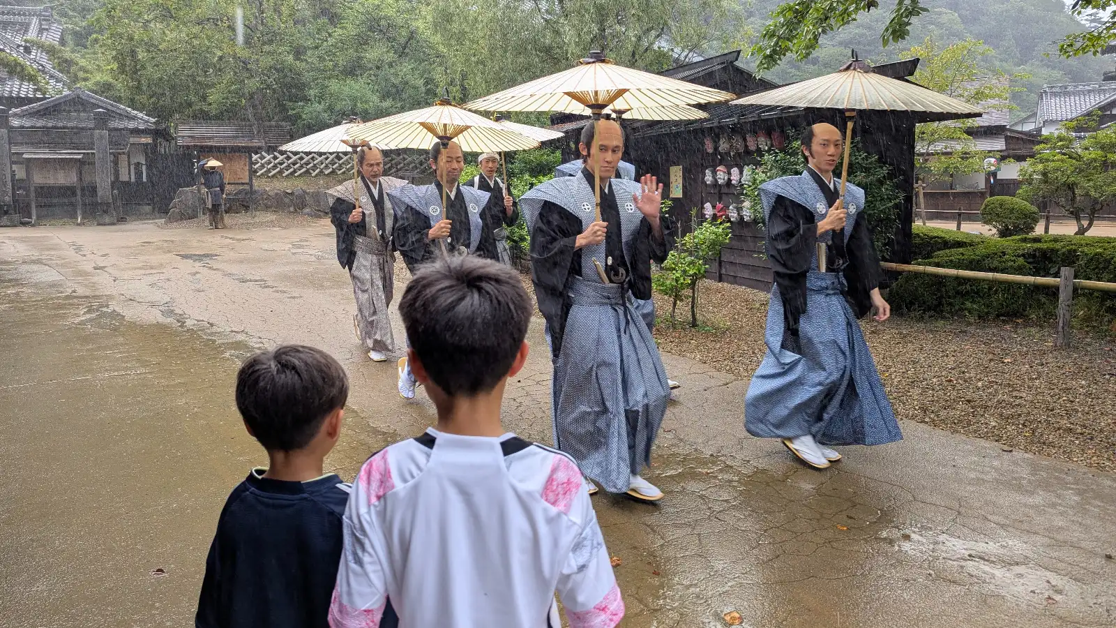 Kids watching a samurai parade in the rain at Edo Wonderland Nikko Edomura, a cultural theme park in Nikko for families.