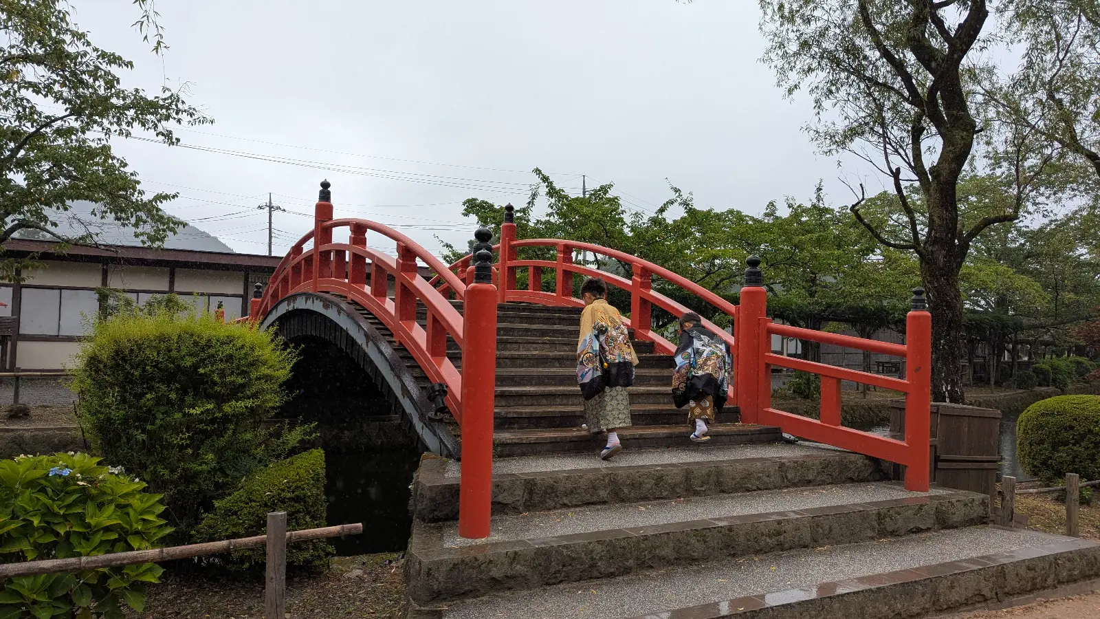 isitors in traditional Edo costumes crossing a red bridge at Edo Wonderland, a kid-friendly theme park in Nikko.