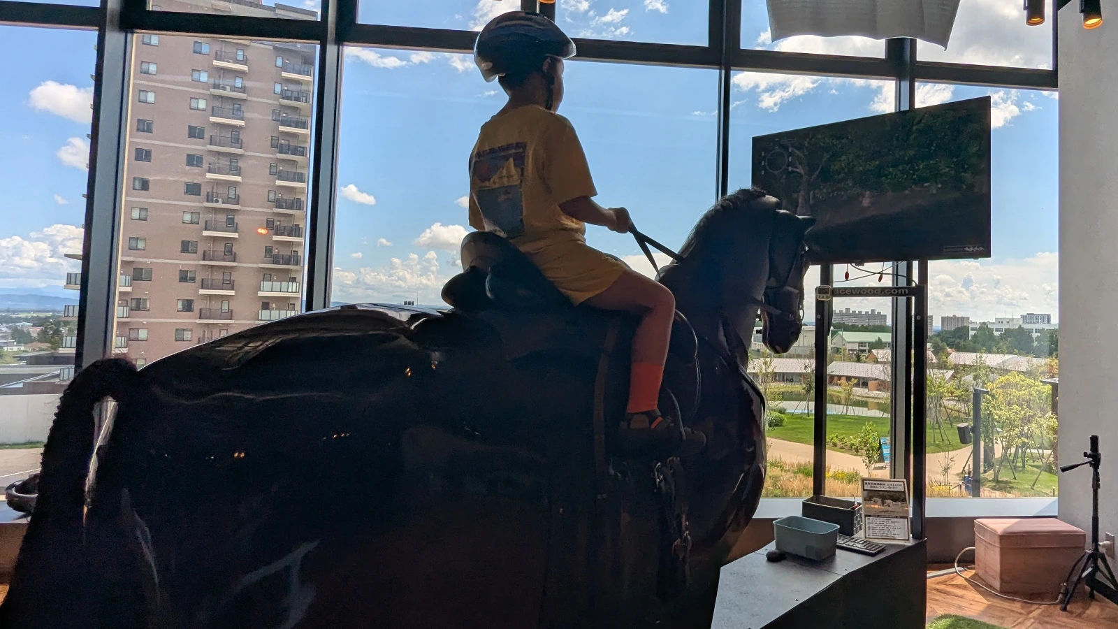 A child rides a virtual horse simulator at KUBOTA AGRI Front in F Village, one of the educational experiences near Es Con Field Hokkaido.