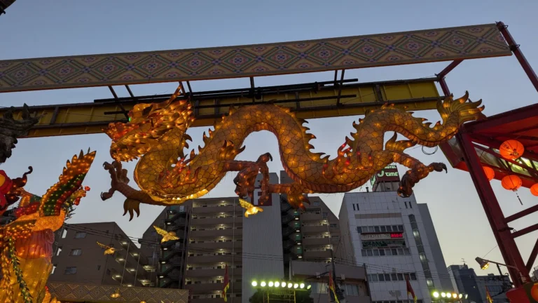 A glowing golden dragon and phoenix lantern display above the main entrance to the Nagasaki Lantern Festival, captured during a family adventure exploring cultural traditions in Nagasaki.