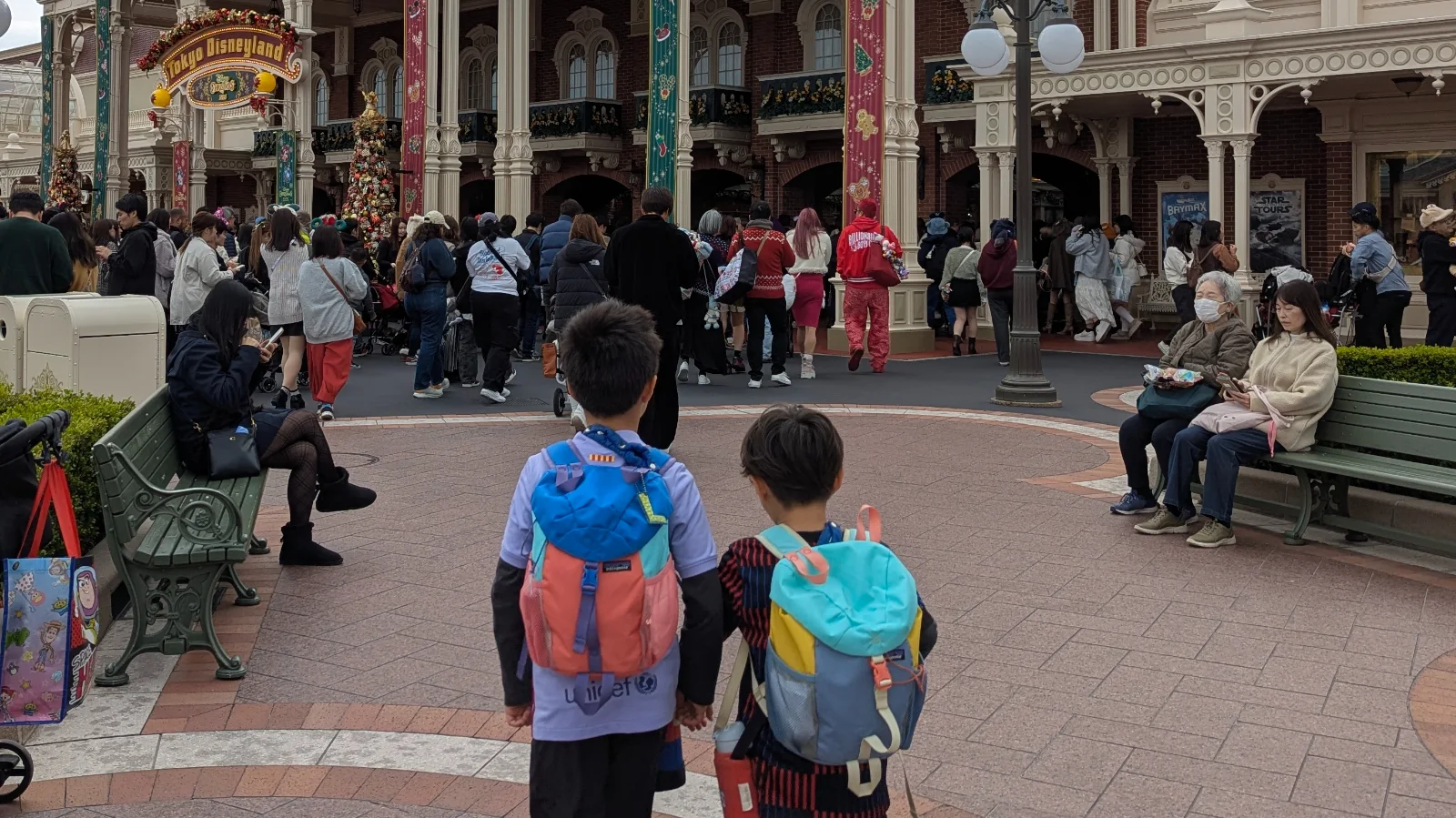Two children standing in a crowded Tokyo Disneyland entrance area in Japan, illustrating the pressure families feel to keep going after investing time and money during a busy trip.