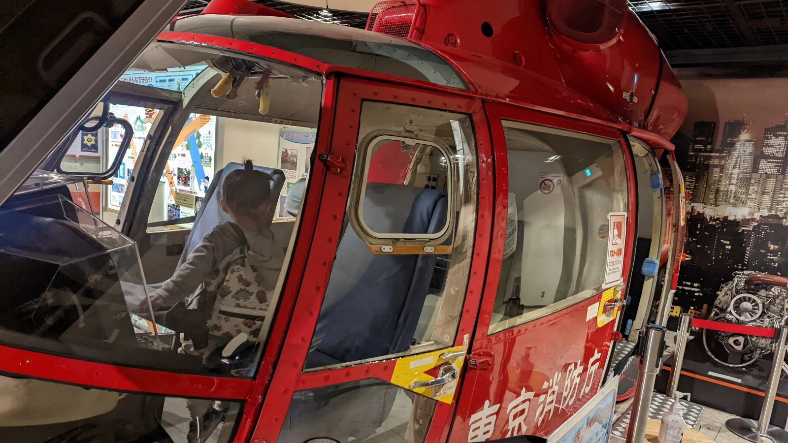 Child sitting inside a real rescue helicopter cockpit at the Fire Museum in Shinjuku, Tokyo, during an interactive exhibit.
