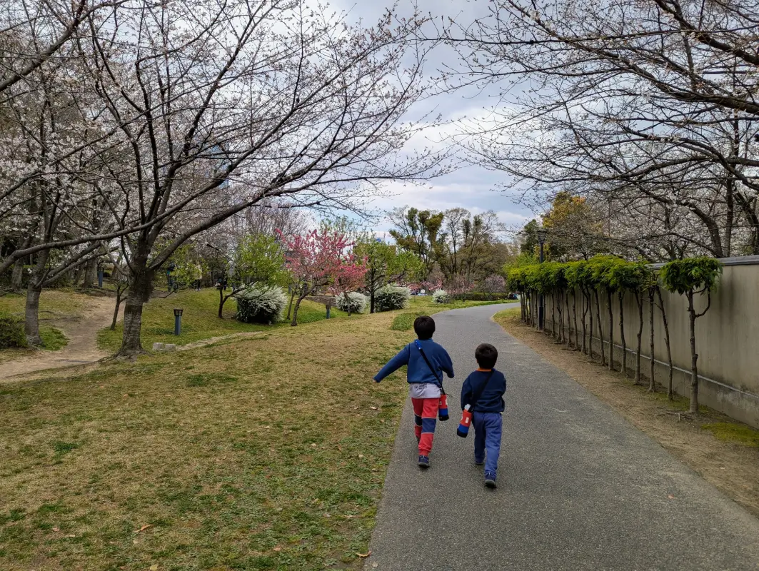 Luca and Nico walking through the garden path at Fujita House Garden in Osaka, surrounded by early-blooming cherry blossoms and peaceful spring scenery.