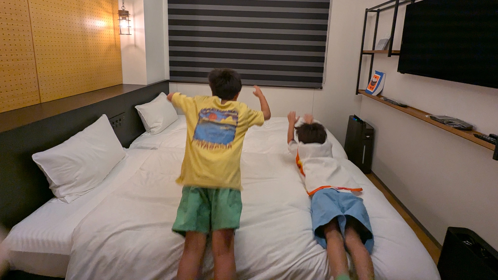 Luca and Nico jumping onto the bed in a Fukuoka hotel room, showing the playful family-friendly atmosphere of staying in Japan with kids.