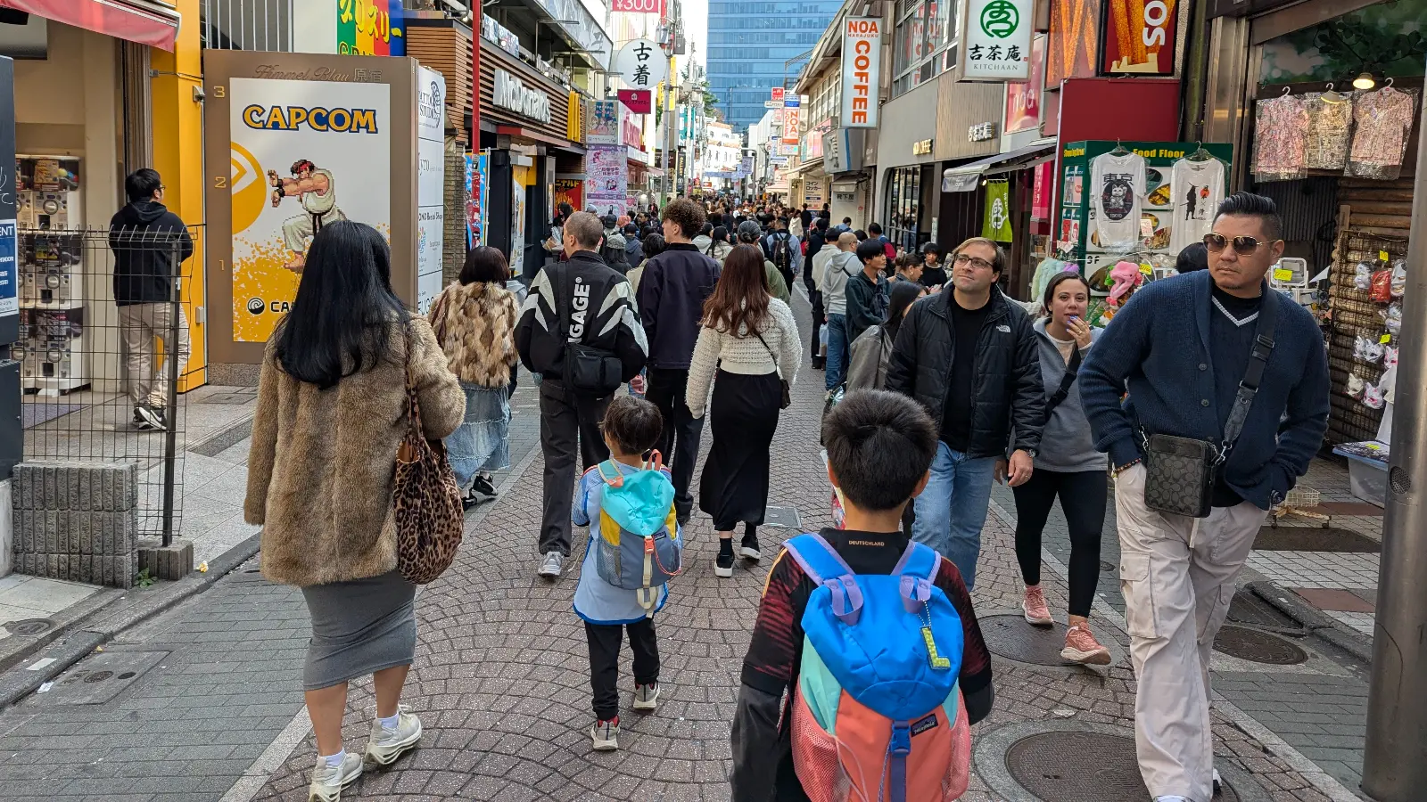 Two children walking through the crowded Takeshita Street in Harajuku, surrounded by shops, street food stands, and weekend visitors.