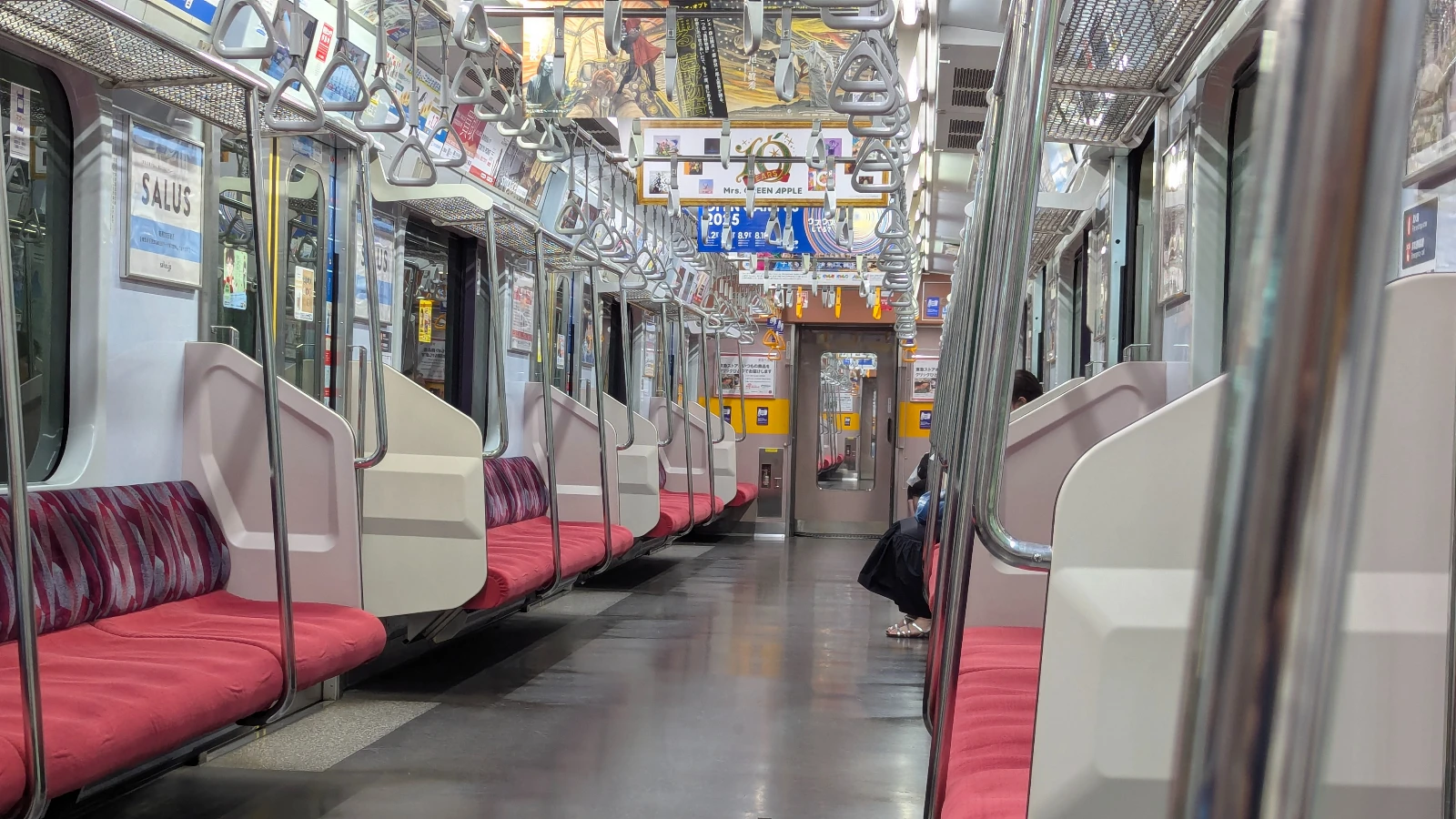 Interior of a Japanese commuter train with bench seating and overhead hand straps.