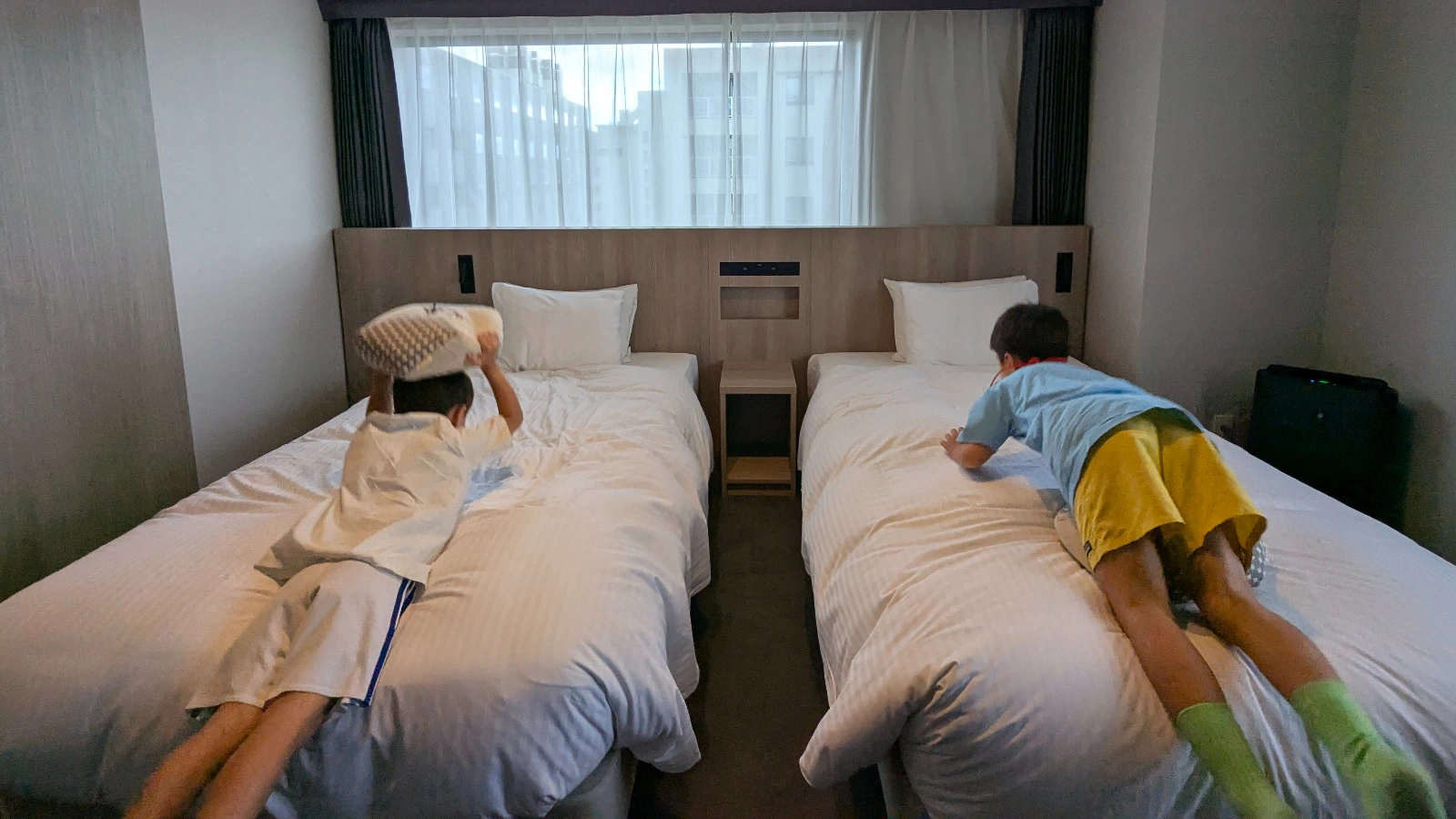 Two children playing on hotel beds in Japan, showing the fun and excitement of a family-friendly stay.