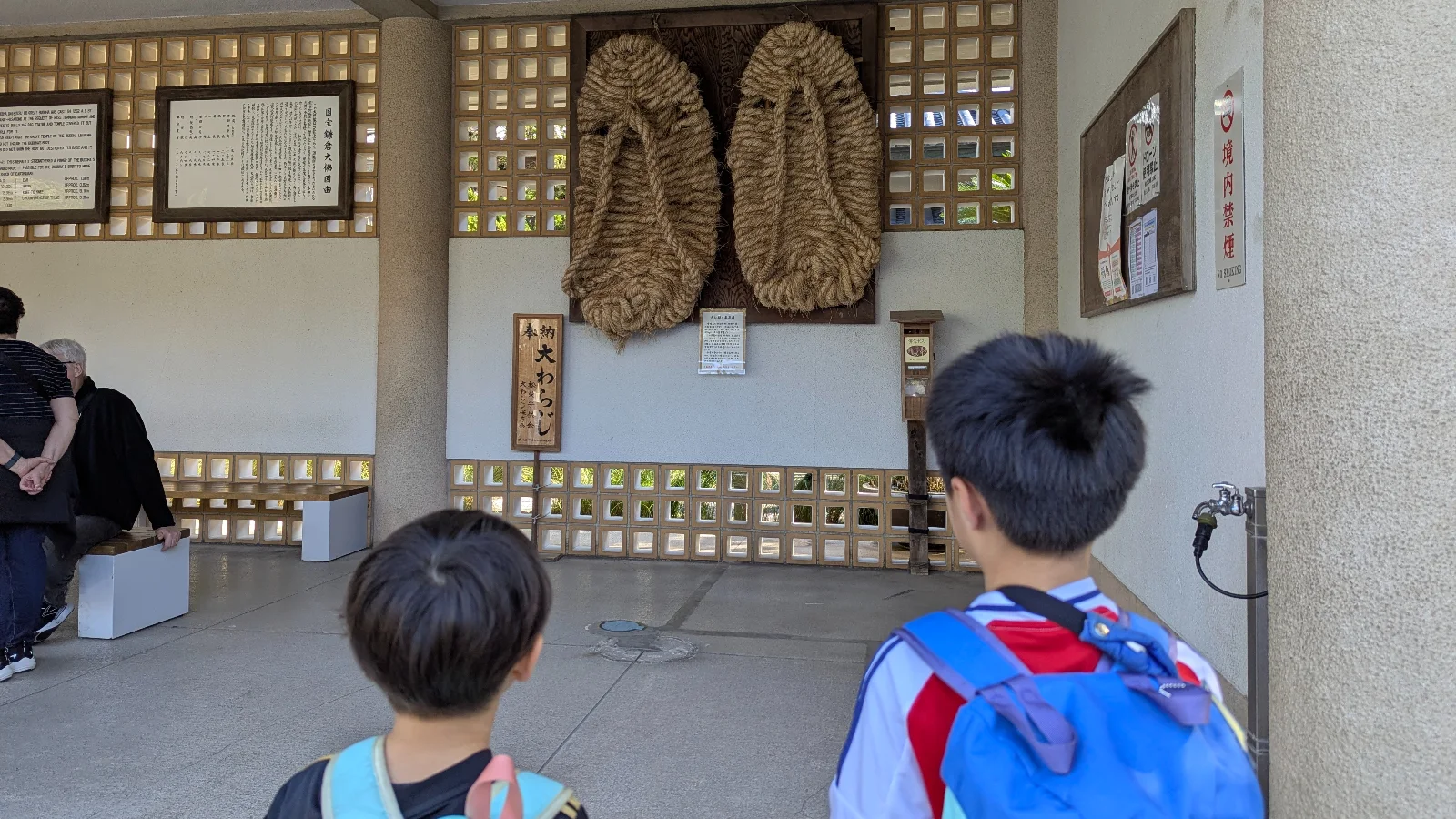 Children observing the giant straw warazori sandals displayed at Kōtoku-in Temple near the Kamakura Great Buddha.