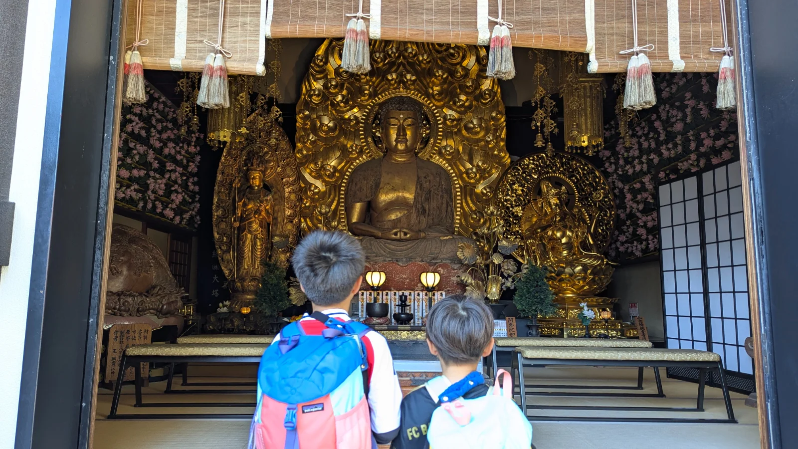 Children viewing the massive golden Kannon statue inside Hasedera Temple in Kamakura during a family visit.