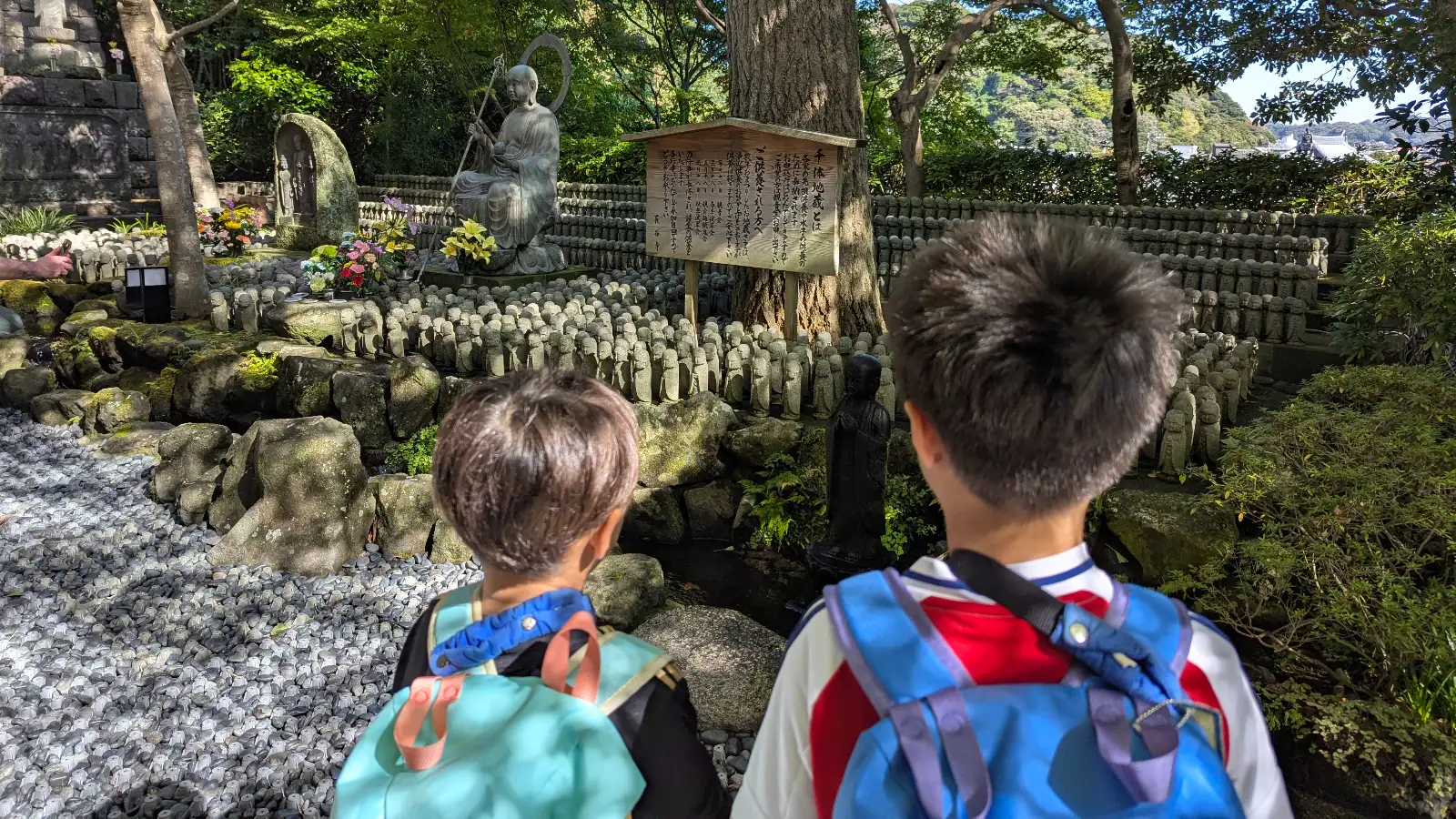 Kids exploring the garden filled with hundreds of small Jizo statues at Hasedera Temple in Kamakura, Japan.