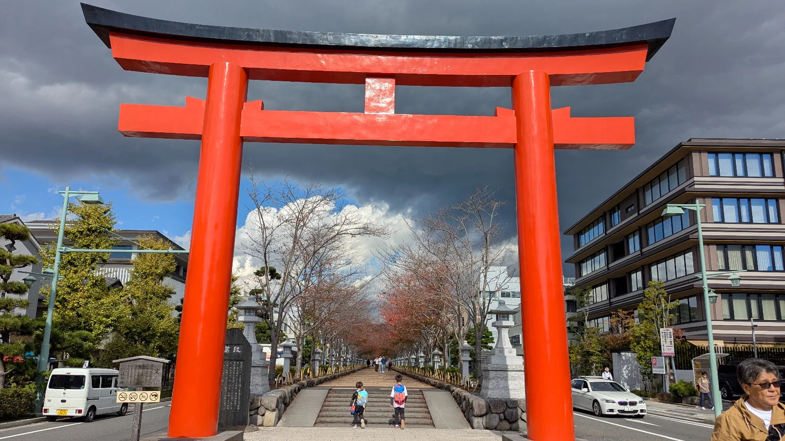 Kids walking under the giant red torii gate at Tsurugaoka Hachimangu in Kamakura, Japan, on a sunny family travel day.
