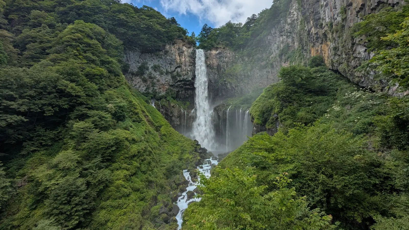 Wide view of Kegon Waterfall in Nikko, Japan, cascading 97 meters into a lush green gorge, a top sight in autumn and winter.