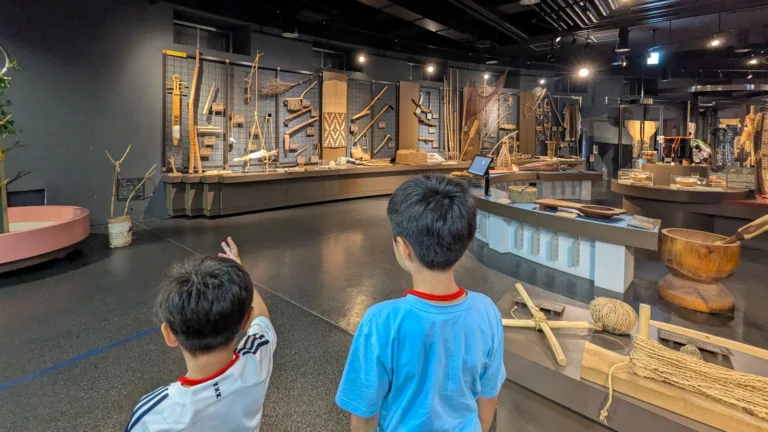 Two kids examine traditional Ainu tools and artifacts at the Sapporo Ainu Culture Promotion Center, discovering Hokkaido’s Indigenous heritage together.
