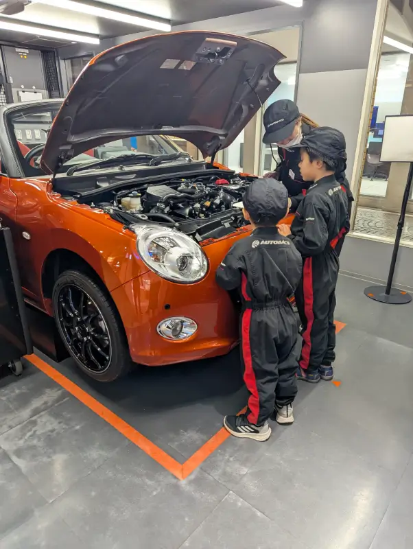Children learning hands-on skills as Car Mechanic at KidZania Fukuoka, a top family-friendly attraction in Japan offering real-world experiences.