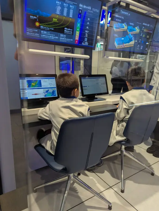 Young Disaster Science Engineers analyzing emergency simulations at KidZania Fukuoka, combining fun and education for families visiting Japan.