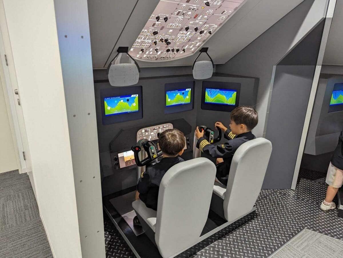 Children learning to fly as pilots in a flight simulator at KidZania Fukuoka, offering hands-on, educational experiences for families visiting Japan.