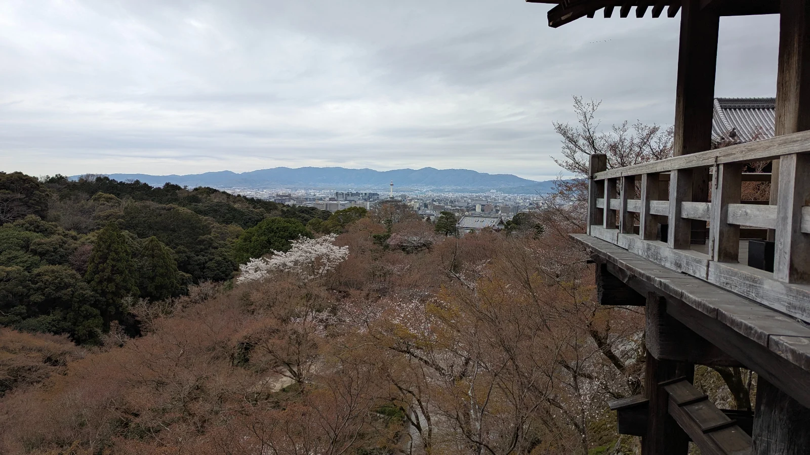 A family with children stands on the wooden veranda of Kiyomizu-dera Temple overlooking Kyoto’s cityscape, capturing a quiet moment during a sunrise family visit to this iconic Kyoto temple.