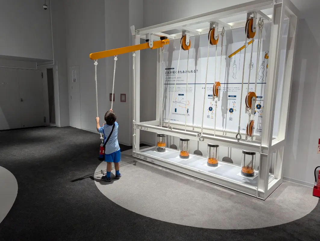 Nico learning about pulleys at a physics exhibit in Kobe’s science center, kobe family travel guide.