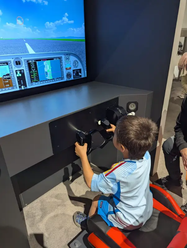 Nico trying out the flight simulator at Kobe Bando Science Museum during a playful family mission in Japan with kids.