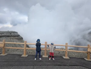 Luca & Nico standing at the edge of Mount Aso’s crater, surrounded by volcanic steam in Kumamoto, Japan.