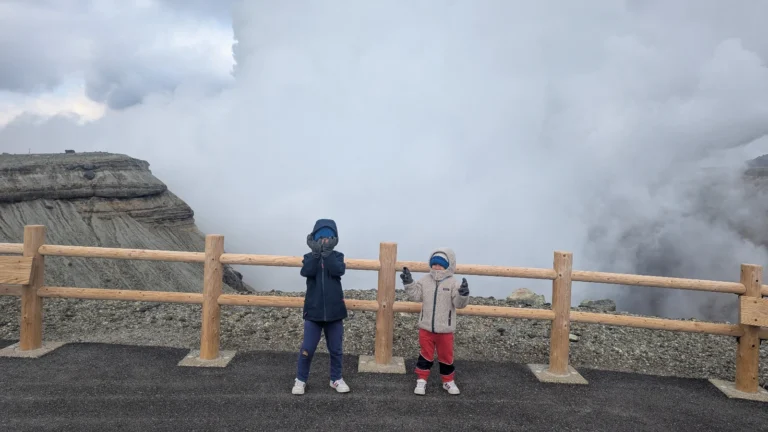 Luca & Nico standing at the edge of Mount Aso’s crater, surrounded by volcanic steam in Kumamoto, Japan.