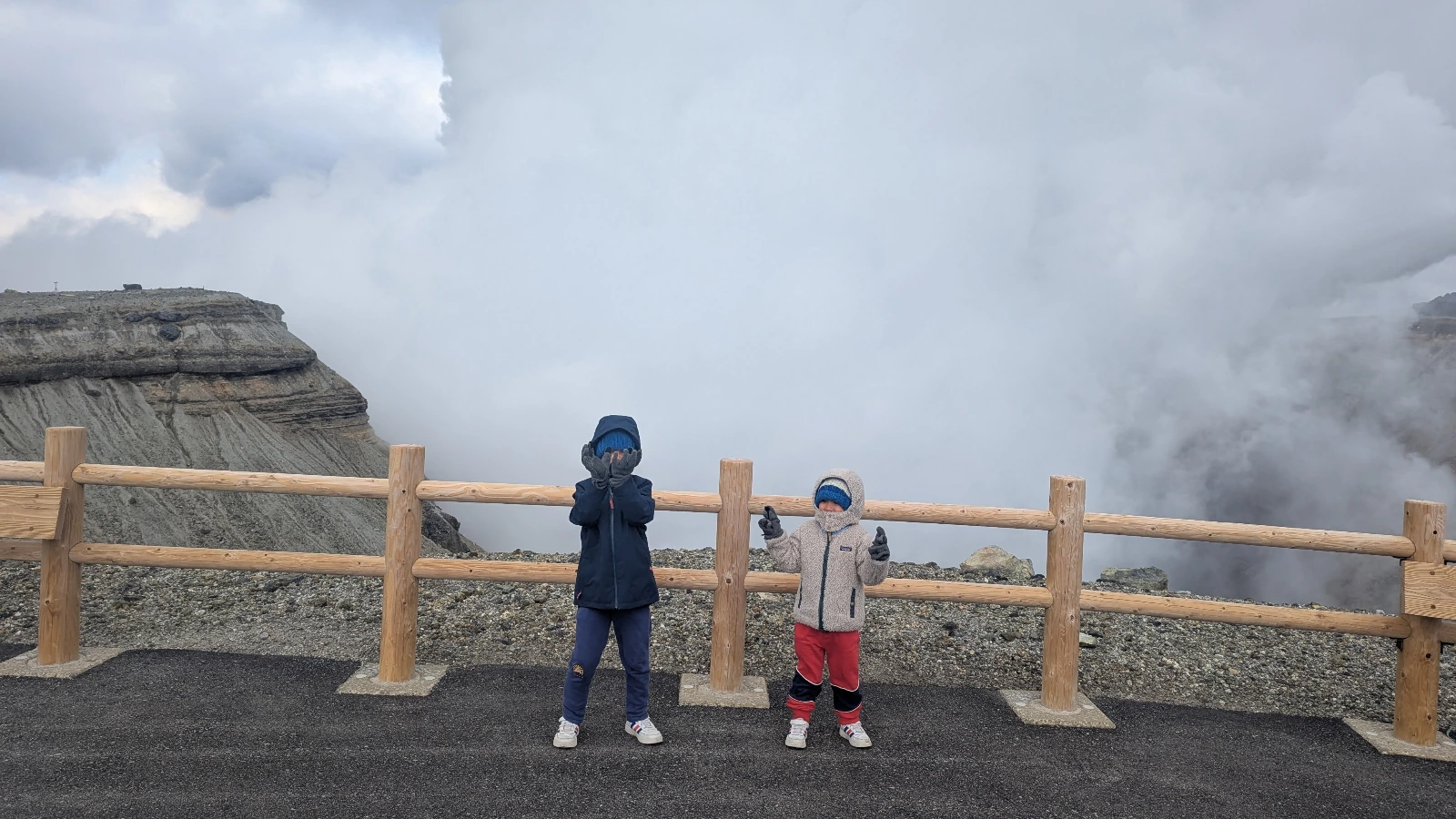 Luca & Nico standing at the edge of Mount Aso’s crater, surrounded by volcanic steam in Kumamoto, Japan.