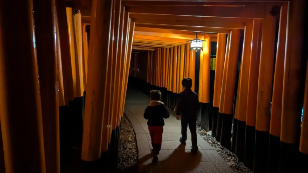 Luca & Nico walking through the iconic red torii gates at Fushimi Inari Shrine during a Kyoto family trip