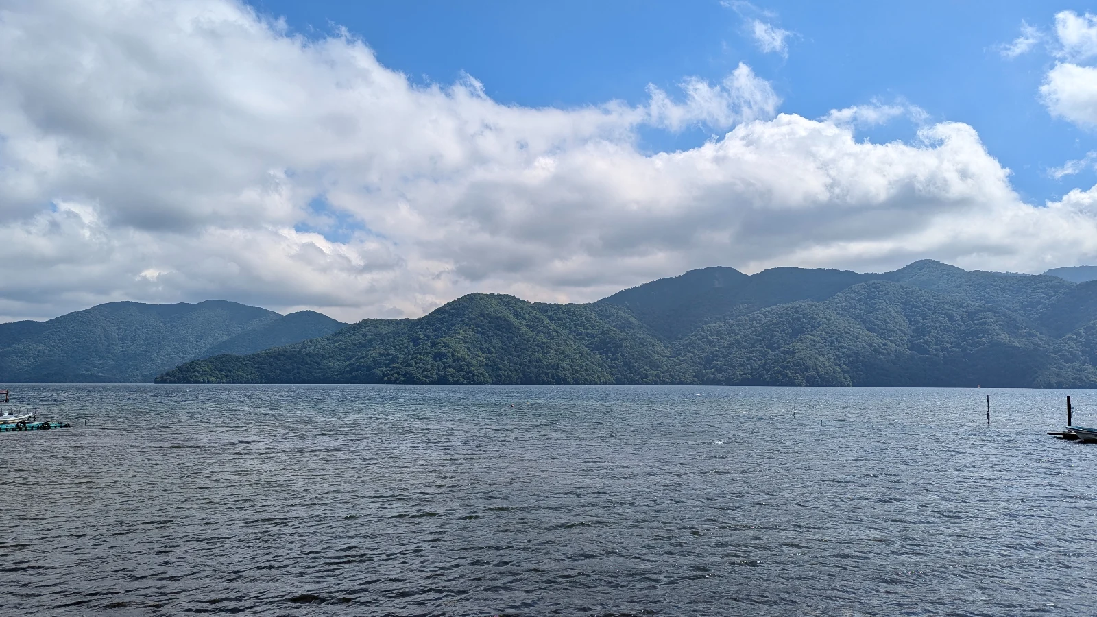 Peaceful view of Lake Chuzenji in Nikko, Japan, with green mountains under a bright blue sky — a scenic stop for families visiting Nikko with kids.