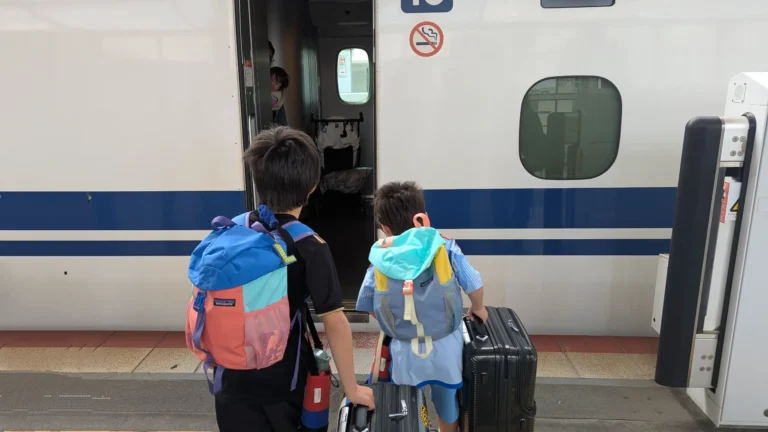 Luca and Nico boarding a Shinkansen train in Japan with their suitcases, showcasing how easy and budget-friendly train travel can be for families exploring Japan.