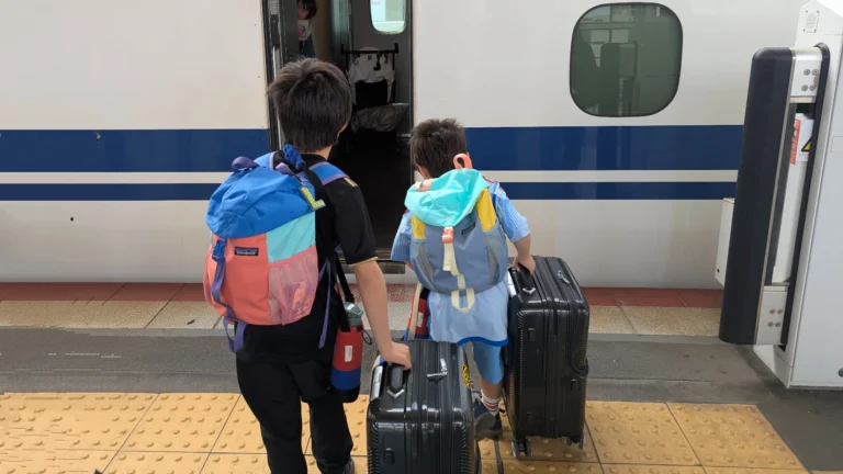 Luca and Nico boarding a Shinkansen train in Japan with their suitcases, showcasing how easy and budget-friendly train travel can be for families exploring Japan.