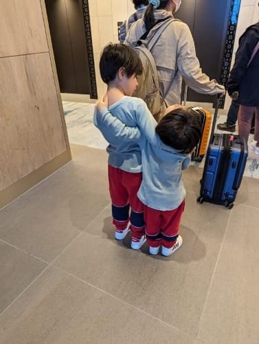 Luca & Nico sharing a warm sibling hug in the lobby of the Hilton Miyakojima hotel in Miyako Island, capturing a sweet moment of family bonding during their travel adventure in Japan.