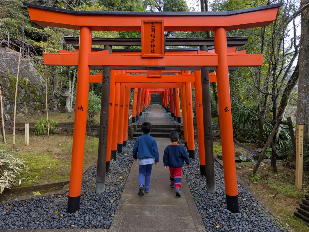 Walking through a tunnel of red torii gates, Luca and Nico discover Japanese traditions in autumn, a favorite season for family travel in Japan with kids.