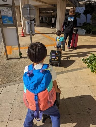 Luca & Nico with colorful Patagonia backpacks and suitcases, arriving at Miyakojima (Miyako Island) ready for their next adventure, capturing the excitement of family travel in Japan.