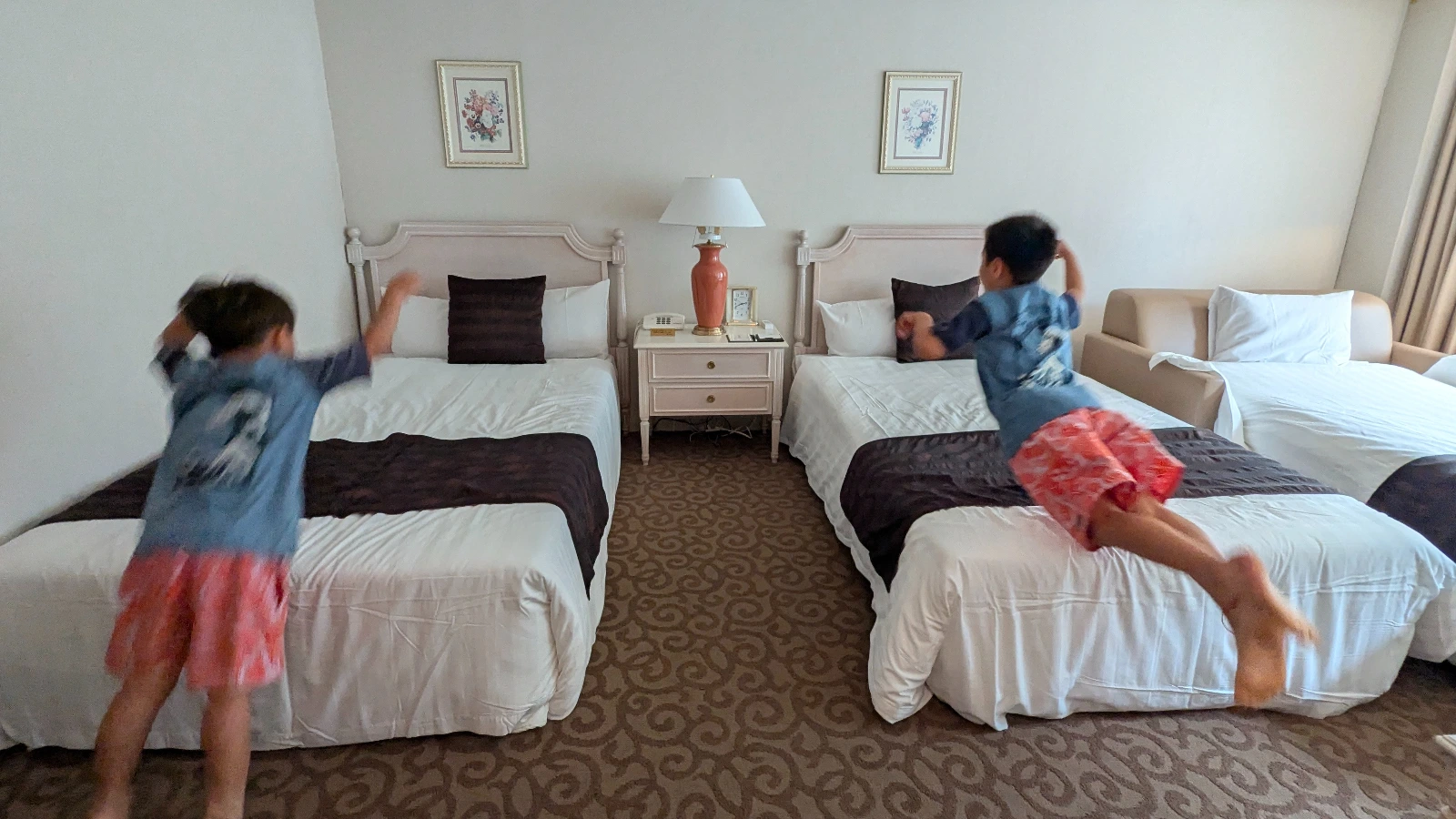 Luca and Nico jumping on the beds in a spacious family room at Luke Plaza Hotel in Nagasaki, showing the playful and family-friendly atmosphere of the stay.
