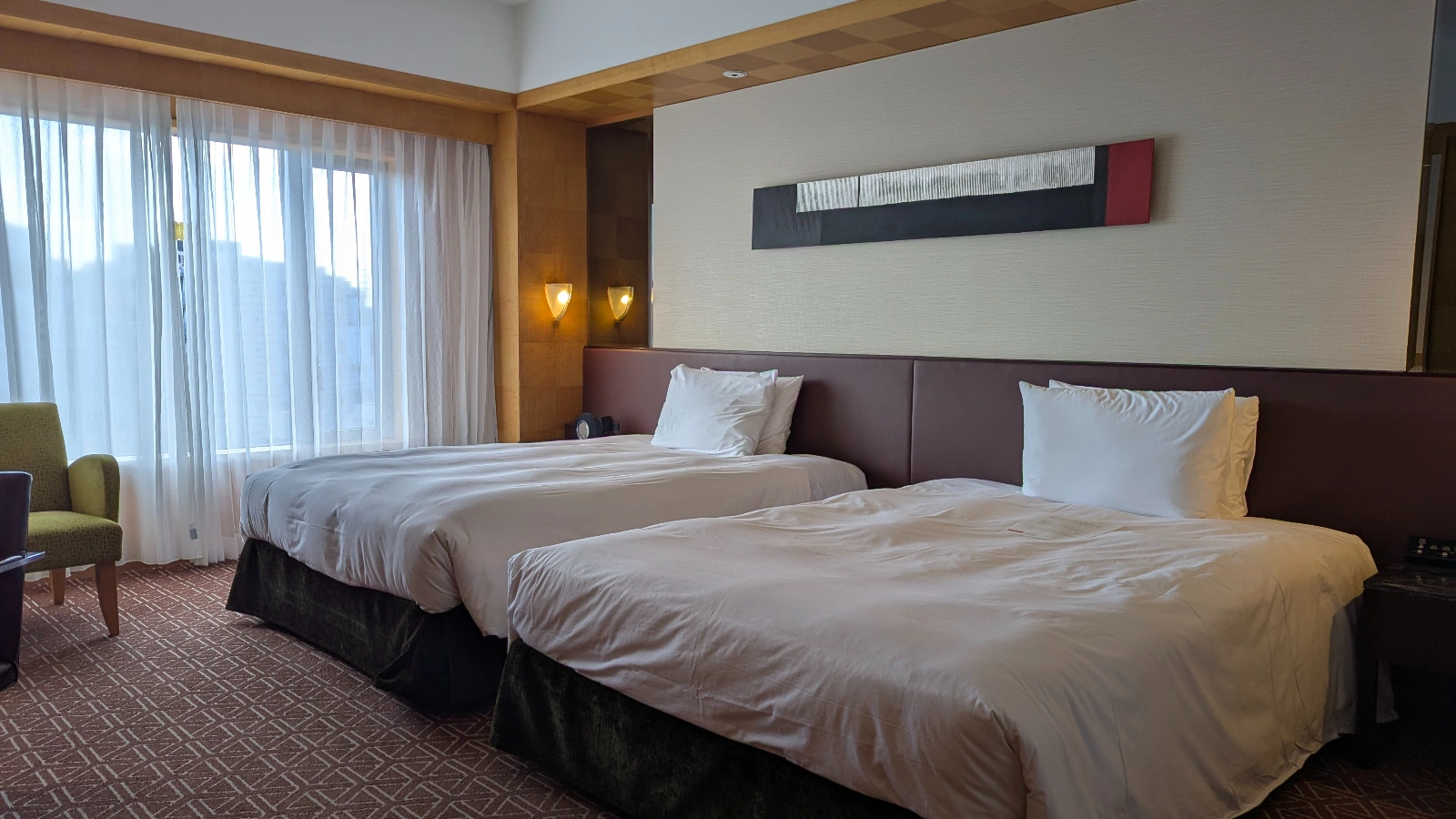 Spacious Japanese hotel room with two beds, large windows, and modern design, ideal for families.