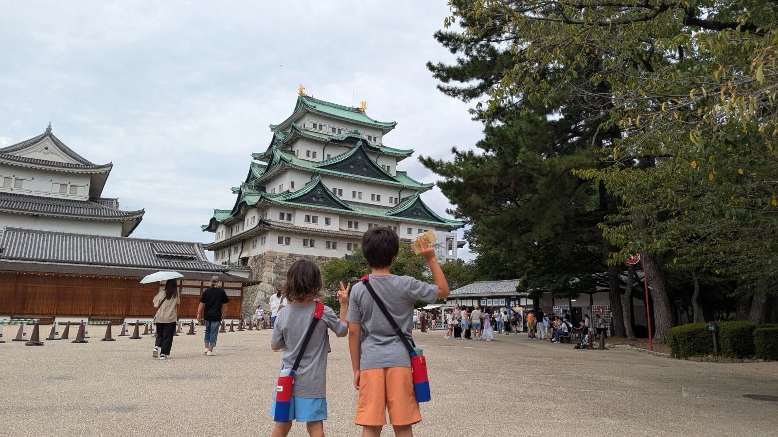 Luca and Nico raise a ticket toward the green-roofed main keep of Nagoya Castle in Nagoya.