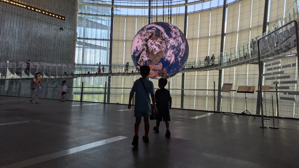 Luca & Nico look up at the giant Geo-Cosmos Earth display inside the National Museum of Emerging Science and Innovation Miraikan (日本科学未来館) in Tokyo, Japan.