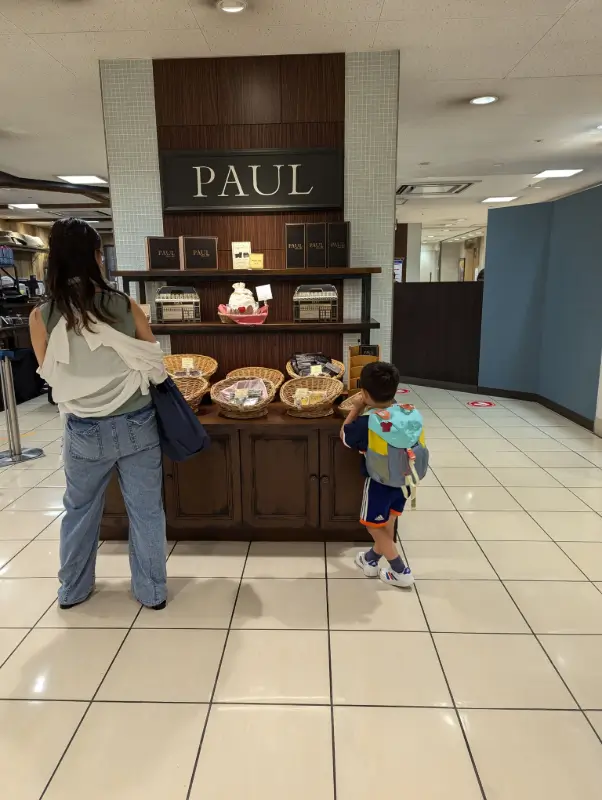 Nico selecting pastries at a PAUL bakery inside a Japanese department store, demonstrating how families can find budget-friendly meals and snacks while exploring Japan.