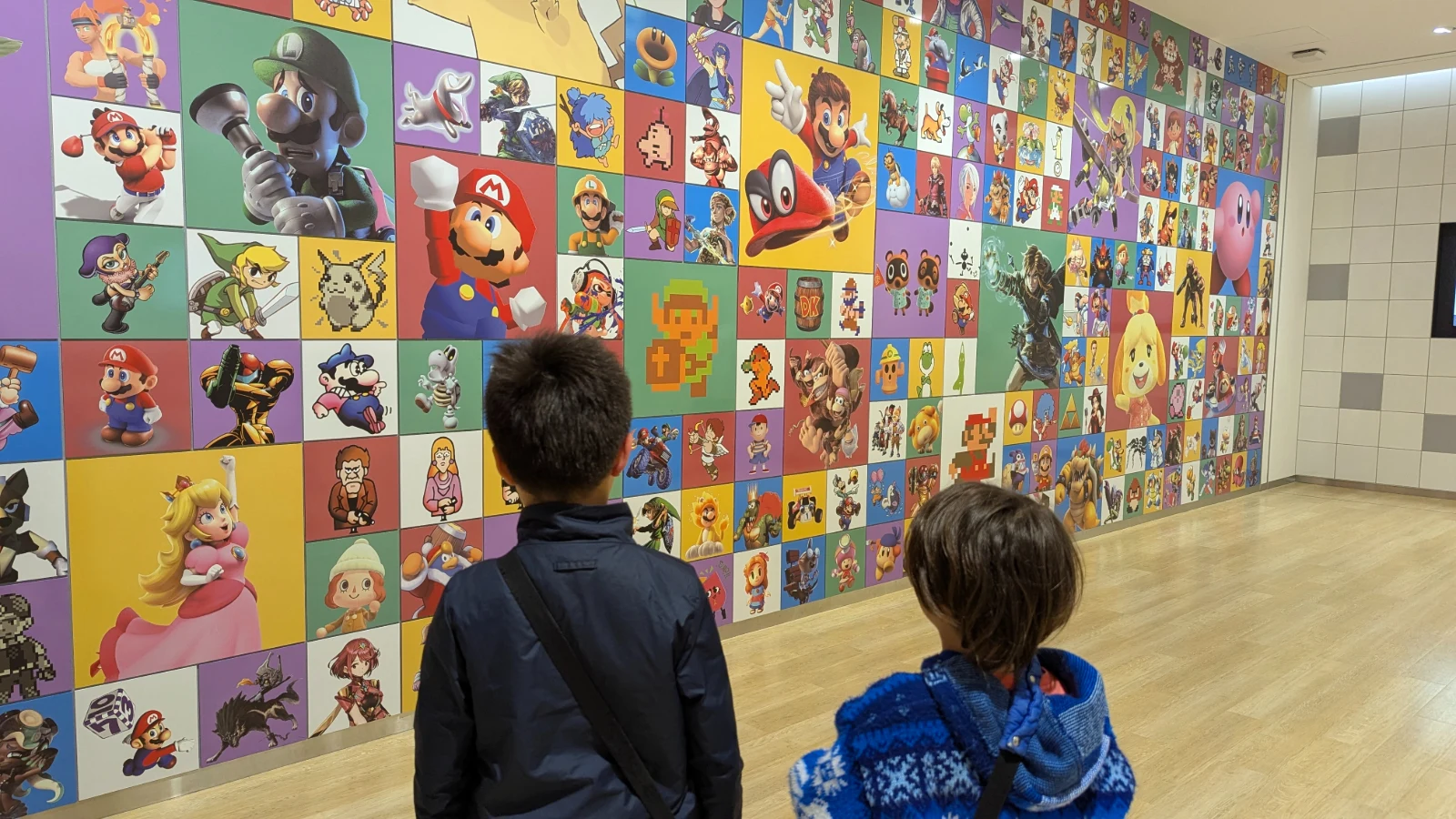 Luca and Nico in front of the character mural at the Nintendo Museum in Uji, Kyoto, Japan.