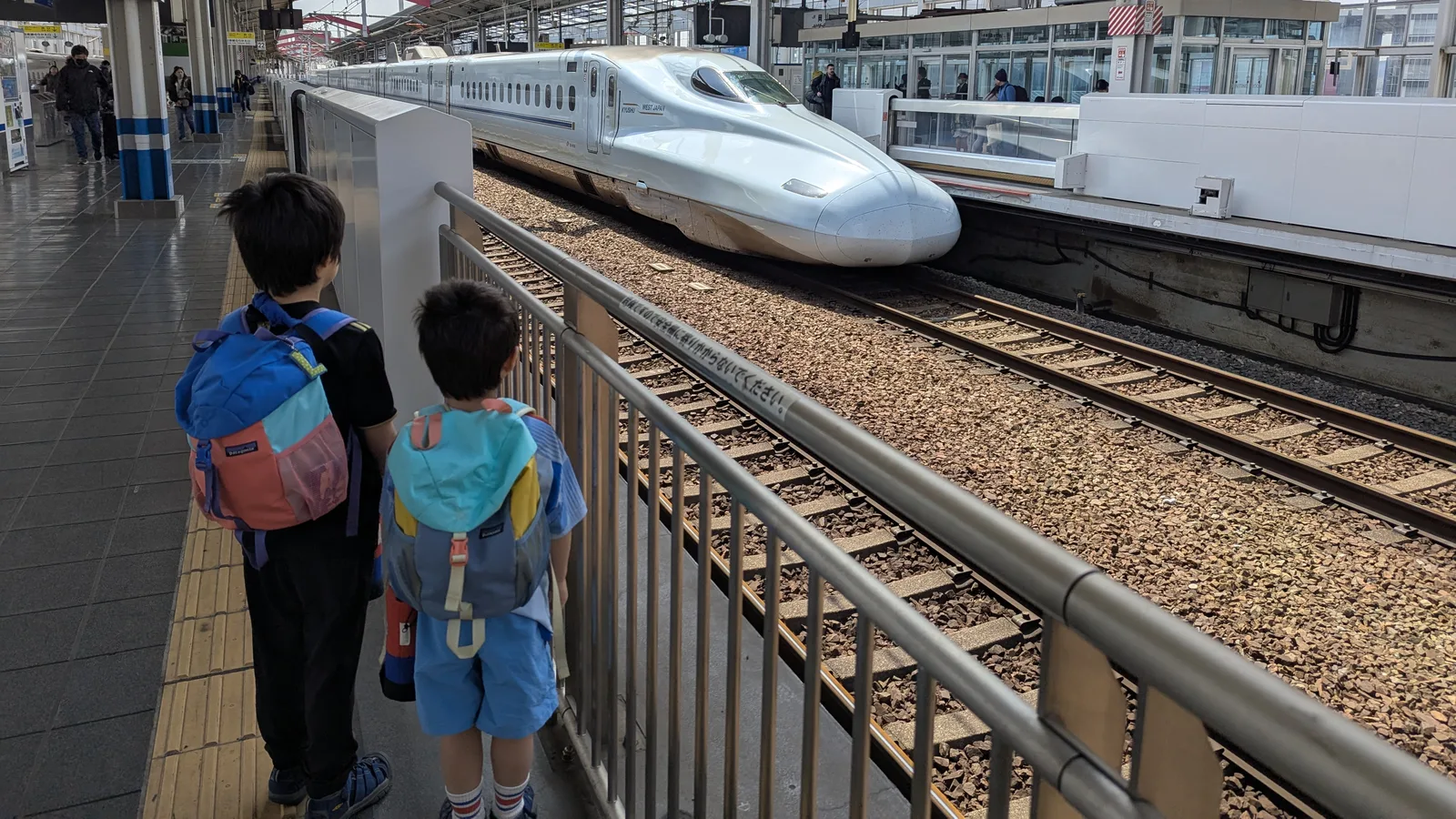 Luca and Nico watching a Shinkansen at the platform at Okayama Station in Okayama, Japan.