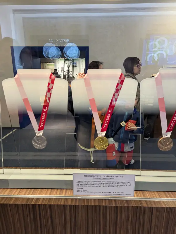 Luca and Nico looking at Tokyo 2020 Olympic medals on display at the Osaka Mint Museum, reflecting Japan’s medal-making legacy.